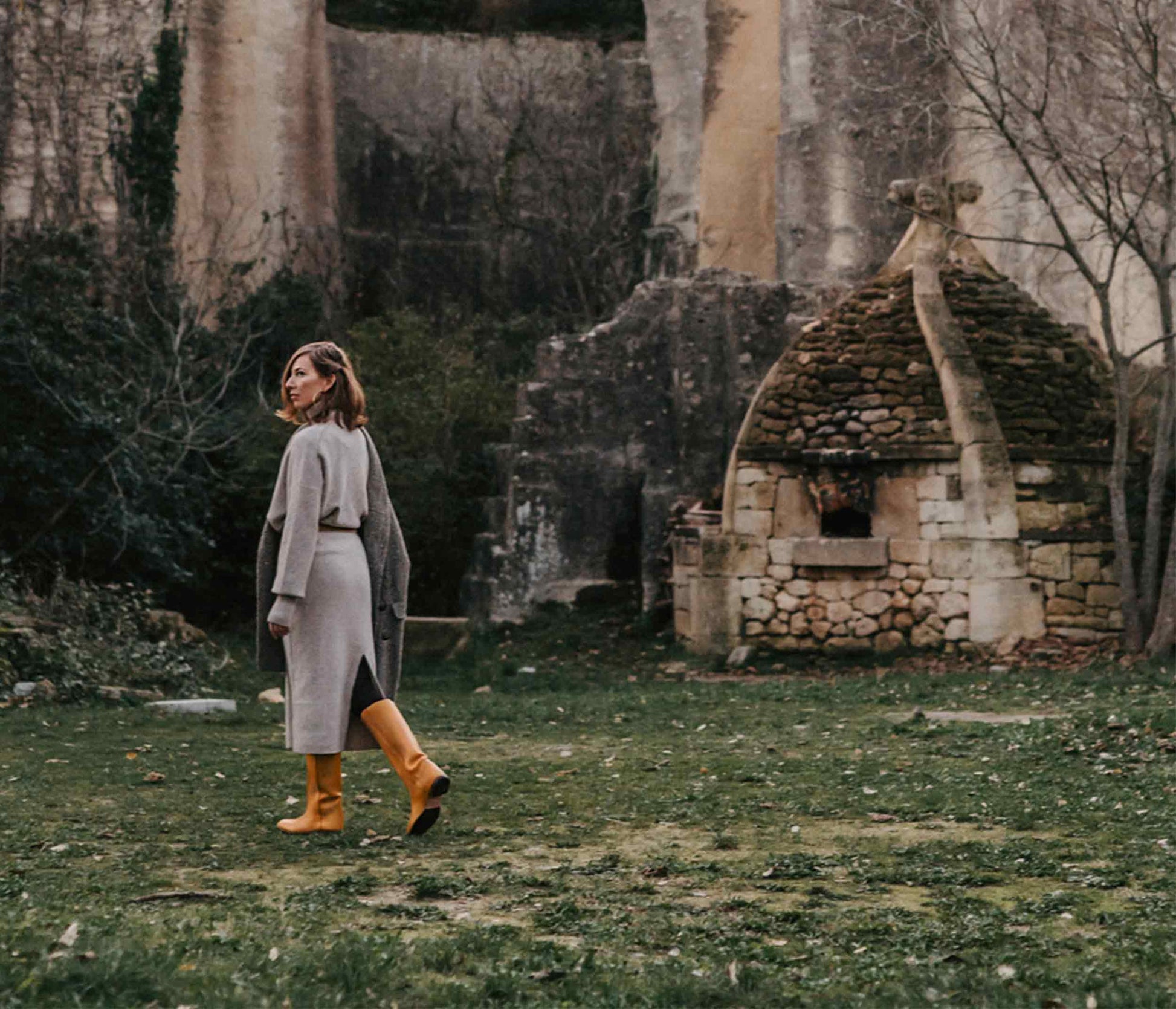 scene femme dans la nature avec des botte en cuir naturel de marque la botte gardiane, robe pull en laine, décors de carrière à junas, france